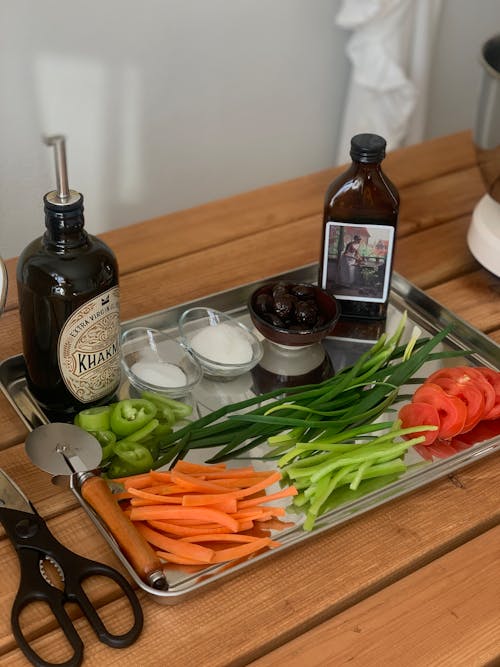 A tray with vegetables, a bottle of olive oil and a knife