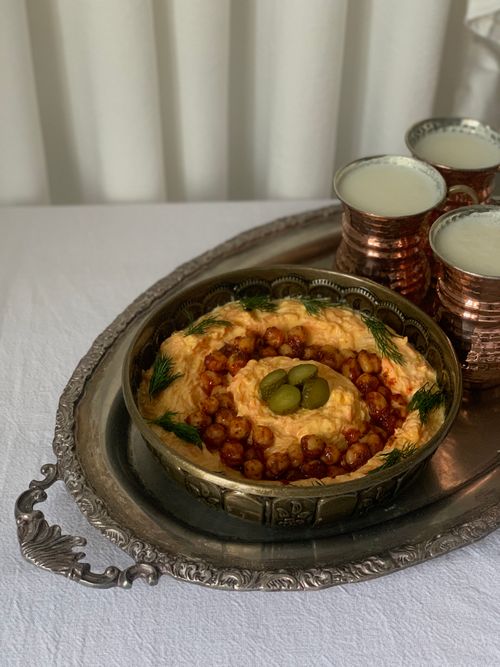 Free Elegant Middle Eastern meal featuring hummus with chickpeas and copper mugs of ayran on a vintage tray. Stock Photo