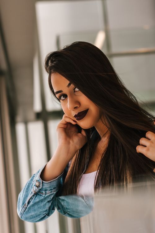 Free Chic portrait of a woman with long hair and dark lipstick posing indoors. Stock Photo