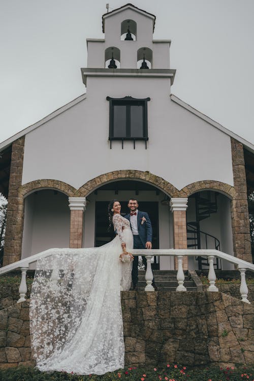 A bride and groom pose in front of a church