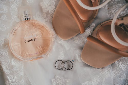 A wedding ring and a bottle of perfume on a bed