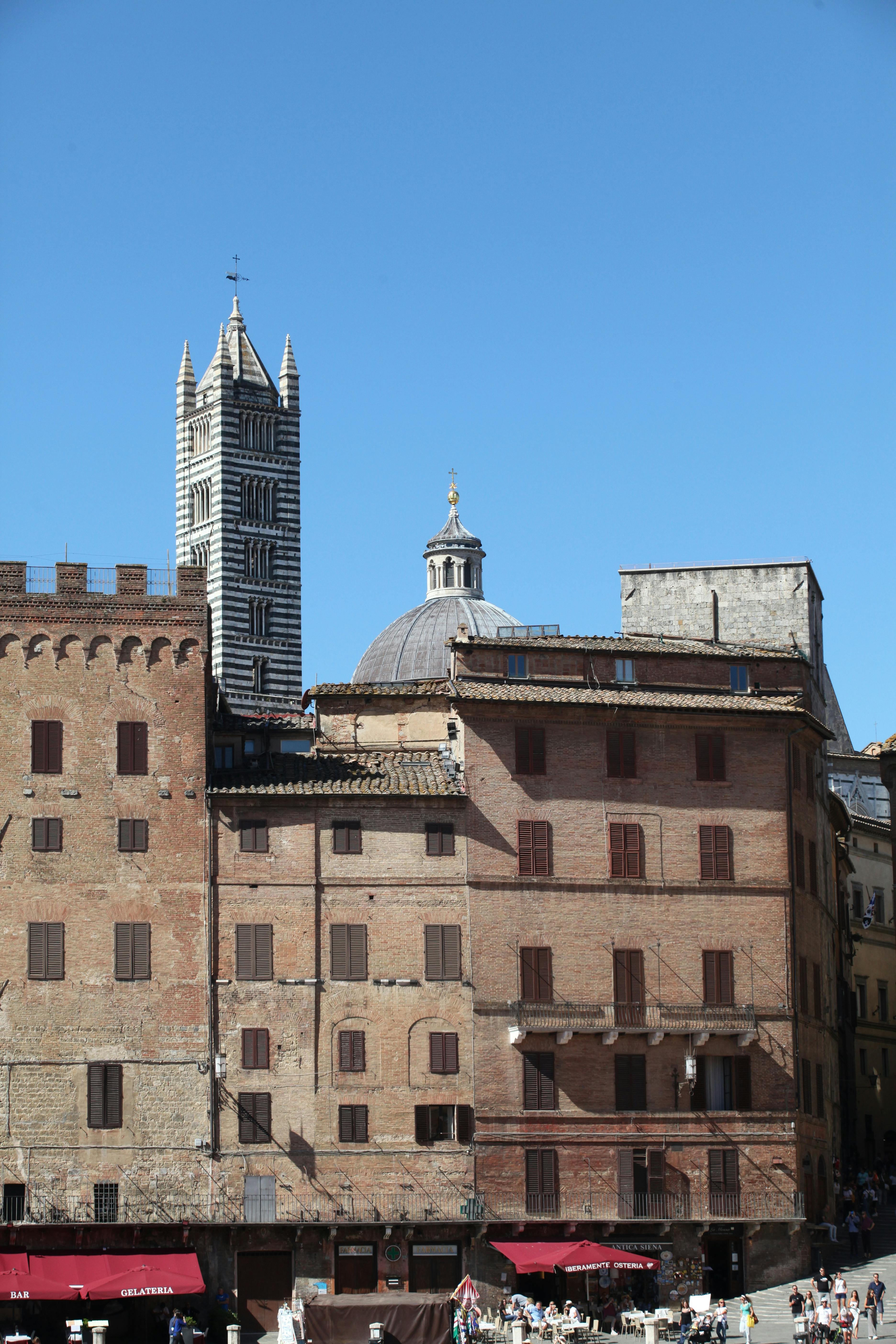 piazza del campo and tower of siena cathedral in siena in italy