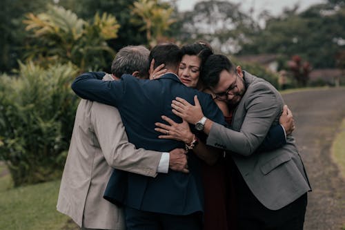 A group of people hugging each other in front of a tree
