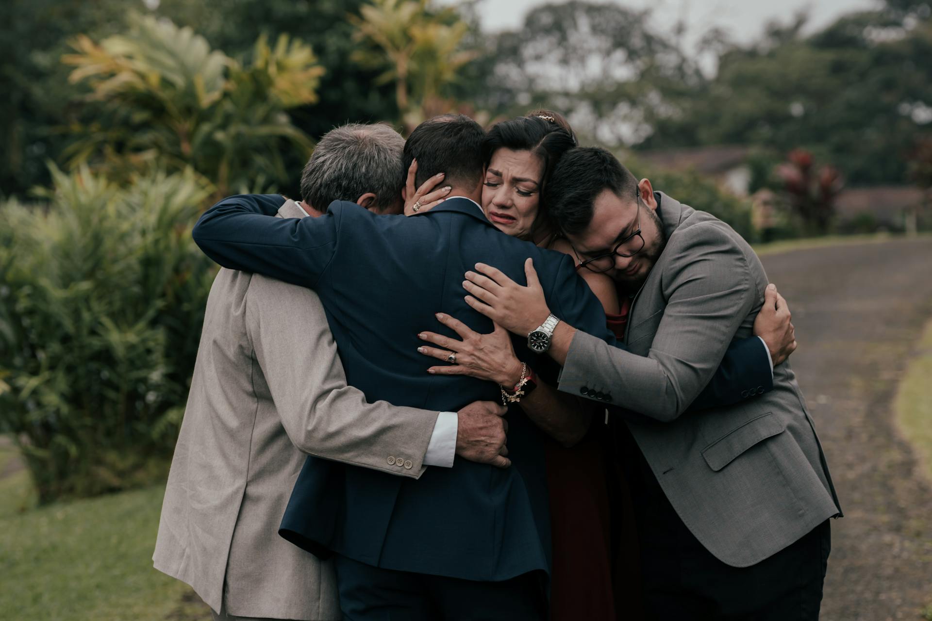 A Group of People in Elegant Clothes Hugging in a Park