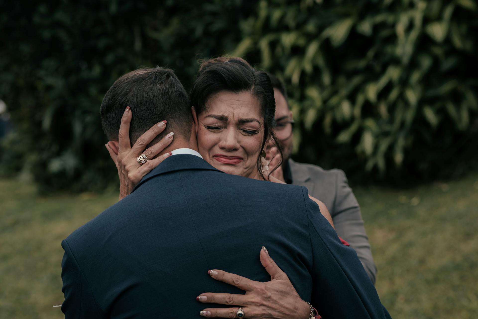 A touching moment of an emotional hug between family members in a garden setting.