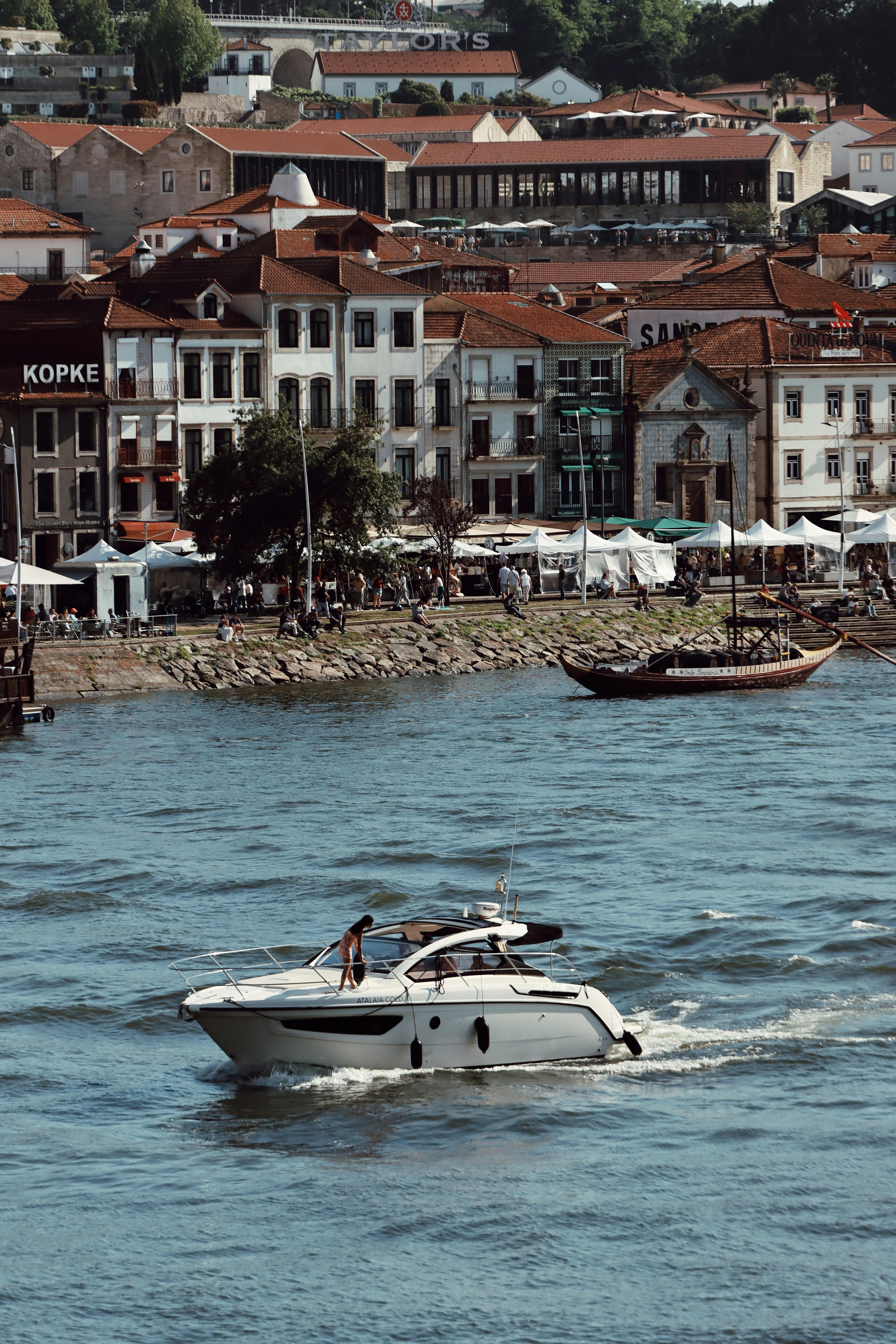 A motorboat cruising on the Douro River with historic buildings in Porto, Portugal.