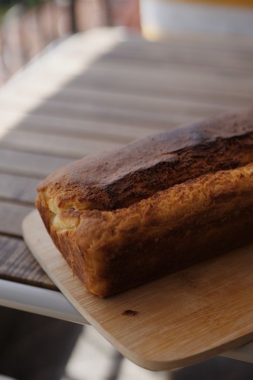 Free A close-up of a freshly baked loaf of bread resting on a wooden cutting board outdoors. Stock Photo