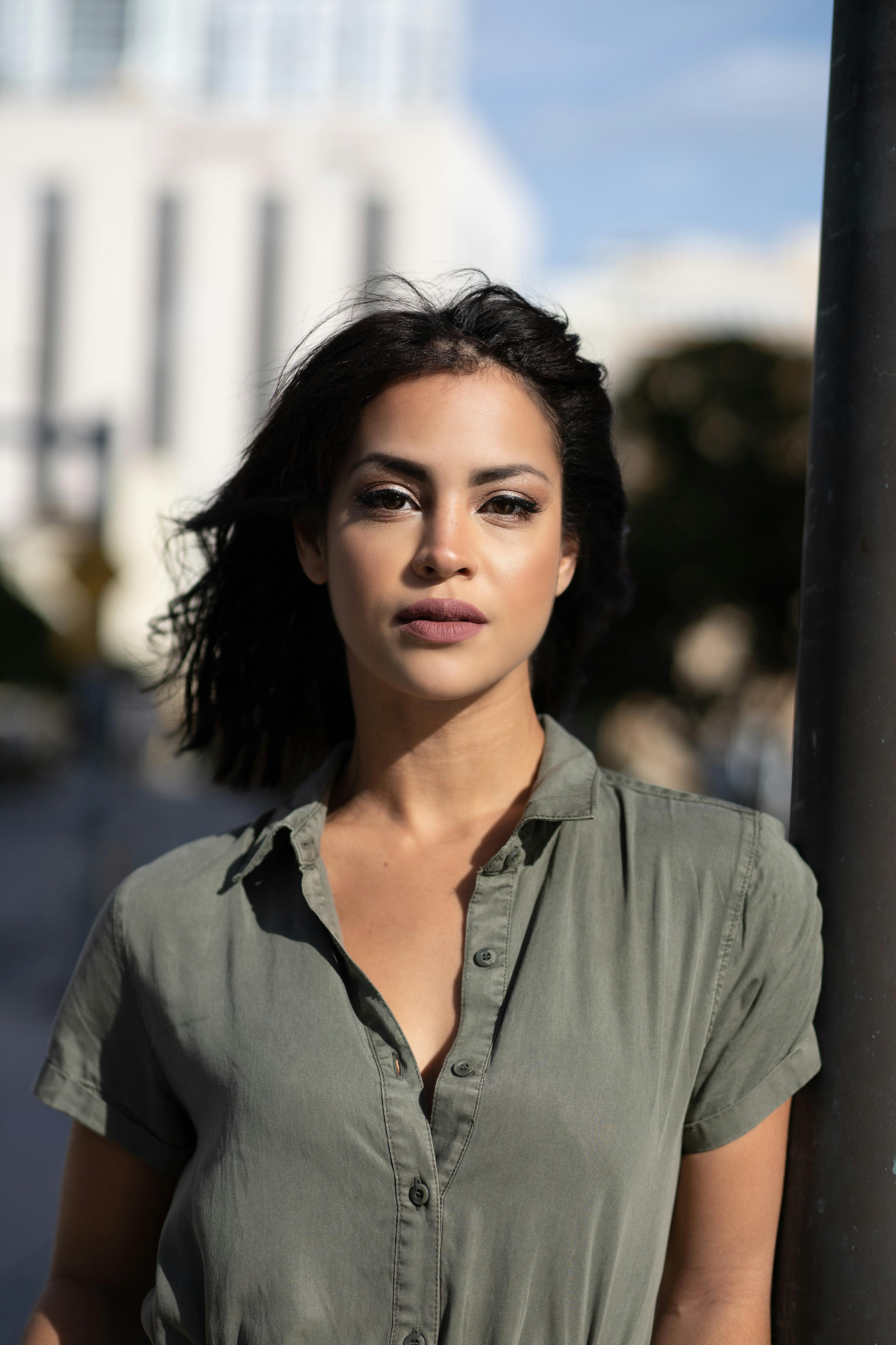 Close-up portrait of a young woman wearing a grey shirt against a city backdrop in Miami.