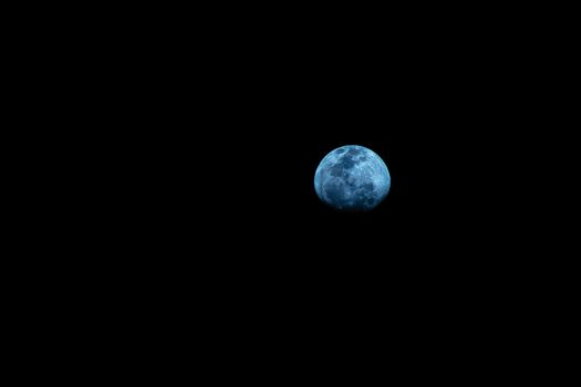 Captivating blue moon against a stark black sky, perfect for night sky enthusiasts.