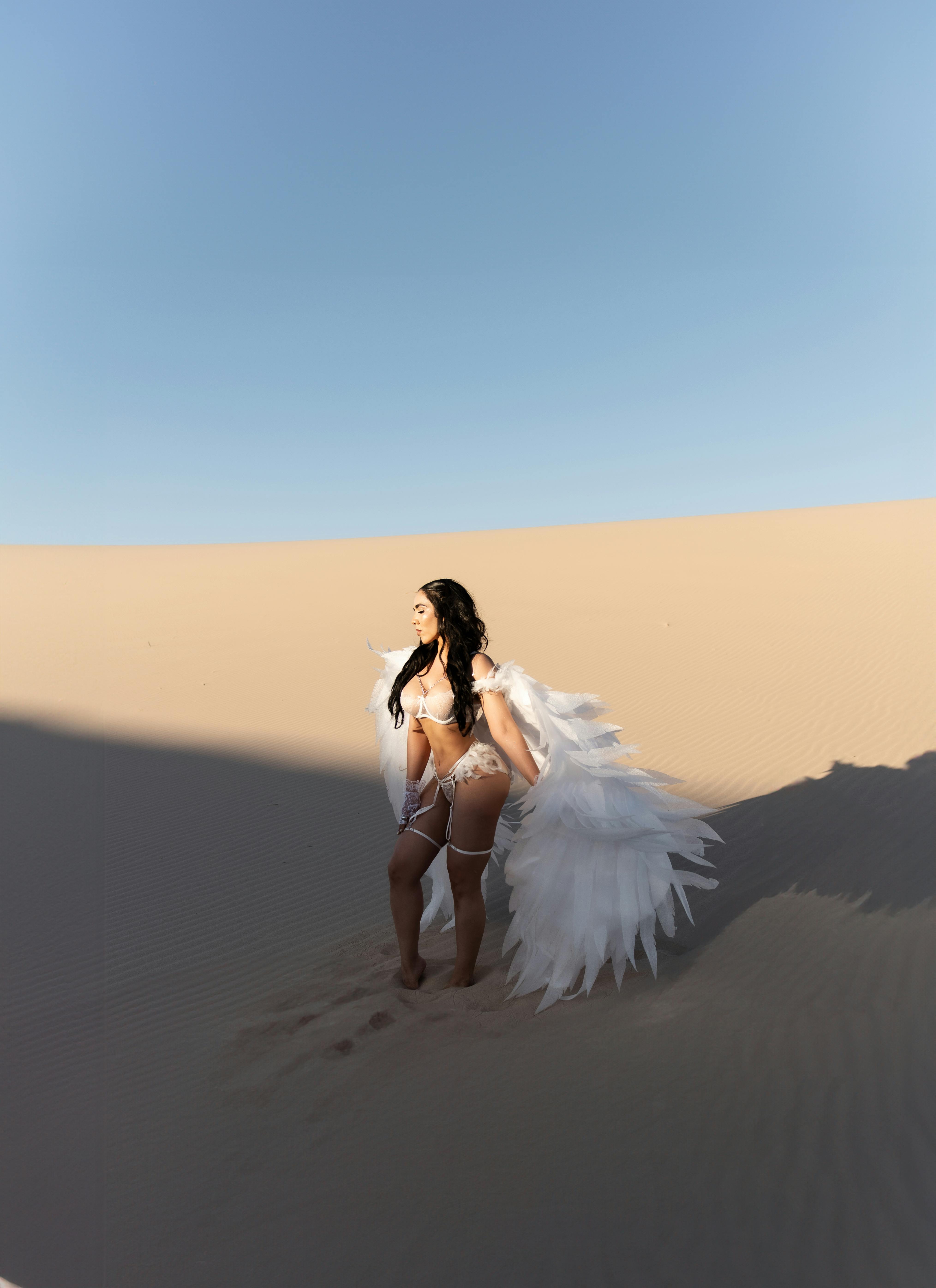 woman in white lingerie with white angel wings posing in a desert