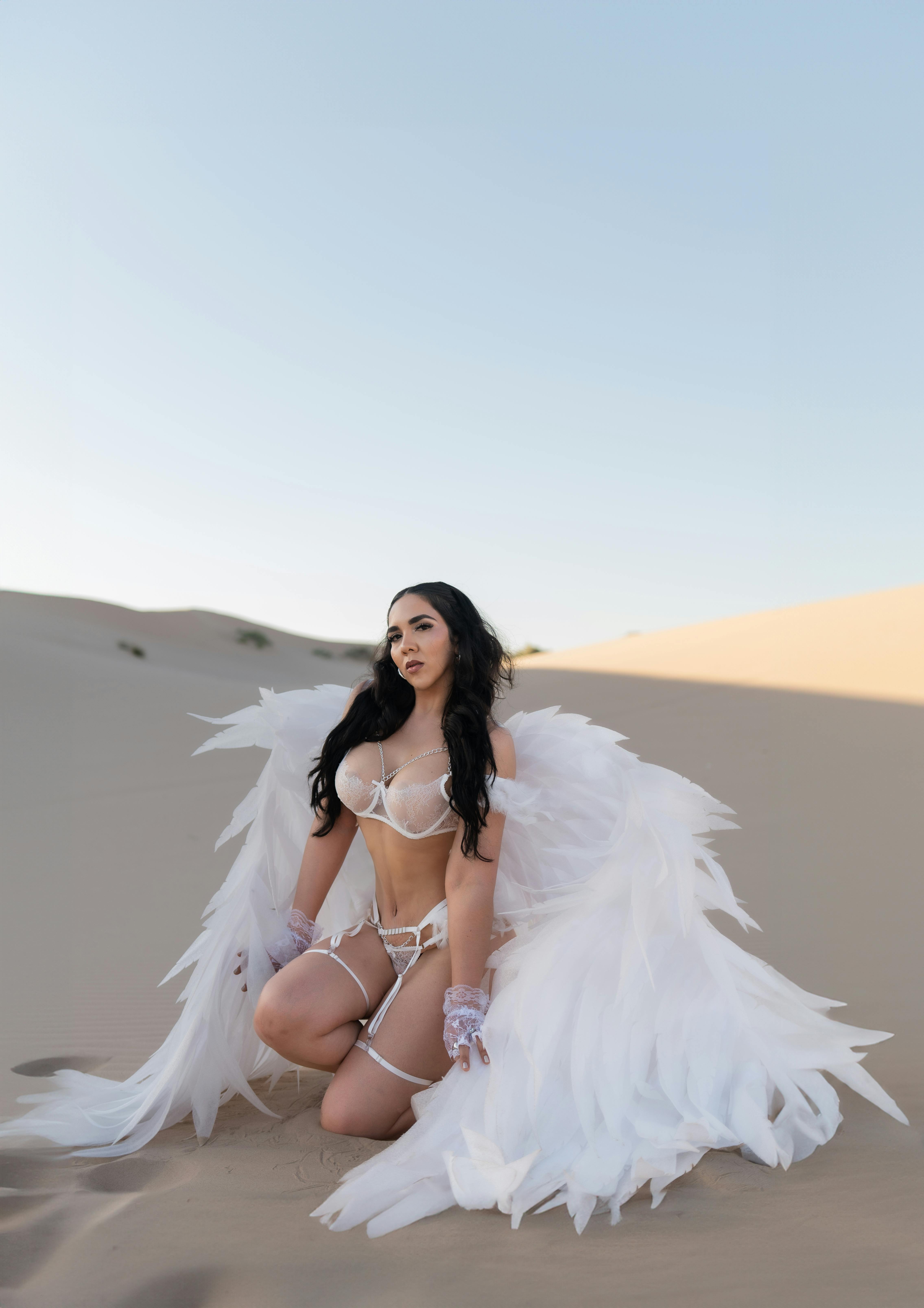 woman in white lingerie with white angel wings posing in a desert