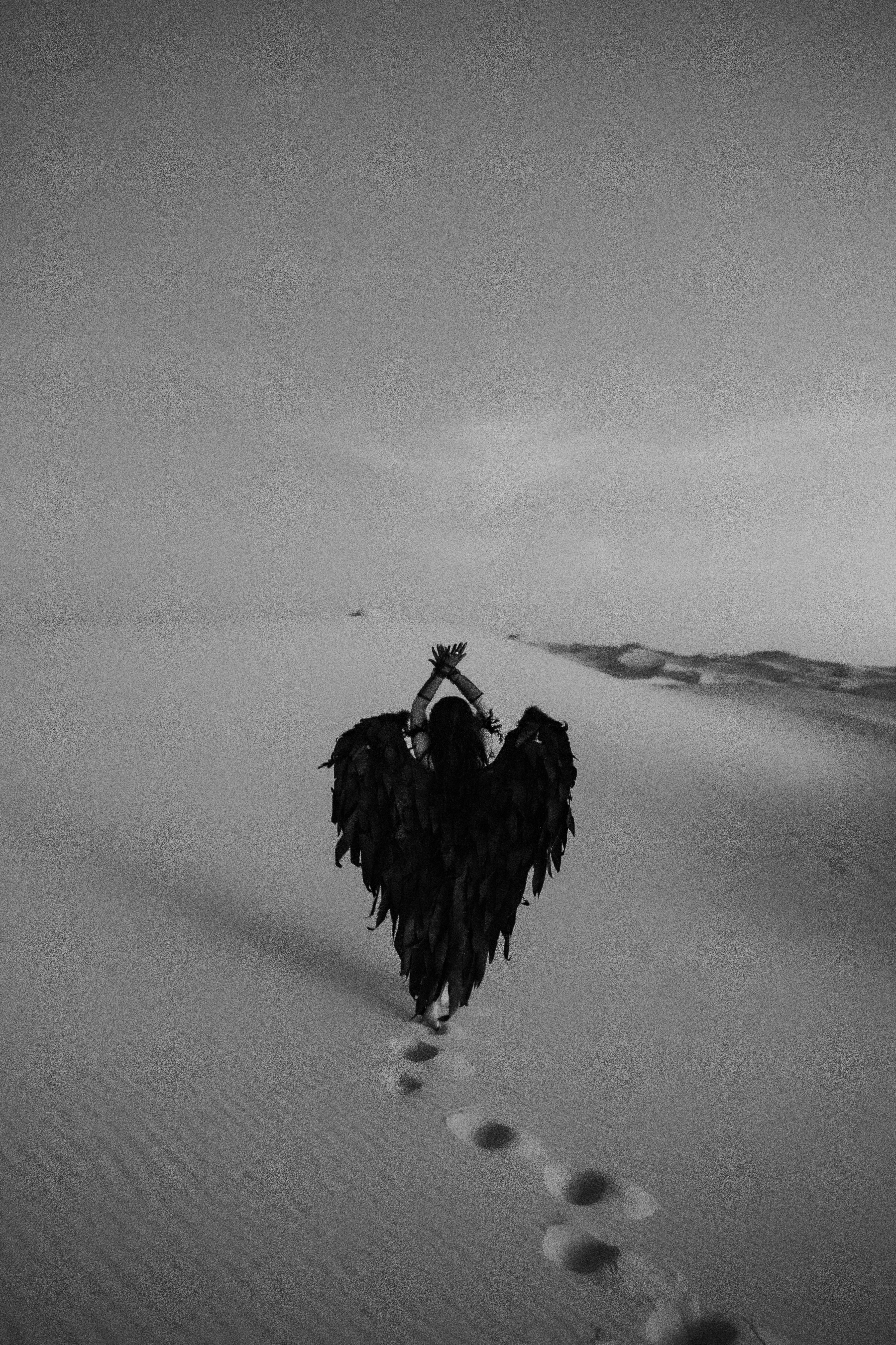 woman with black angel wings posing in a desert