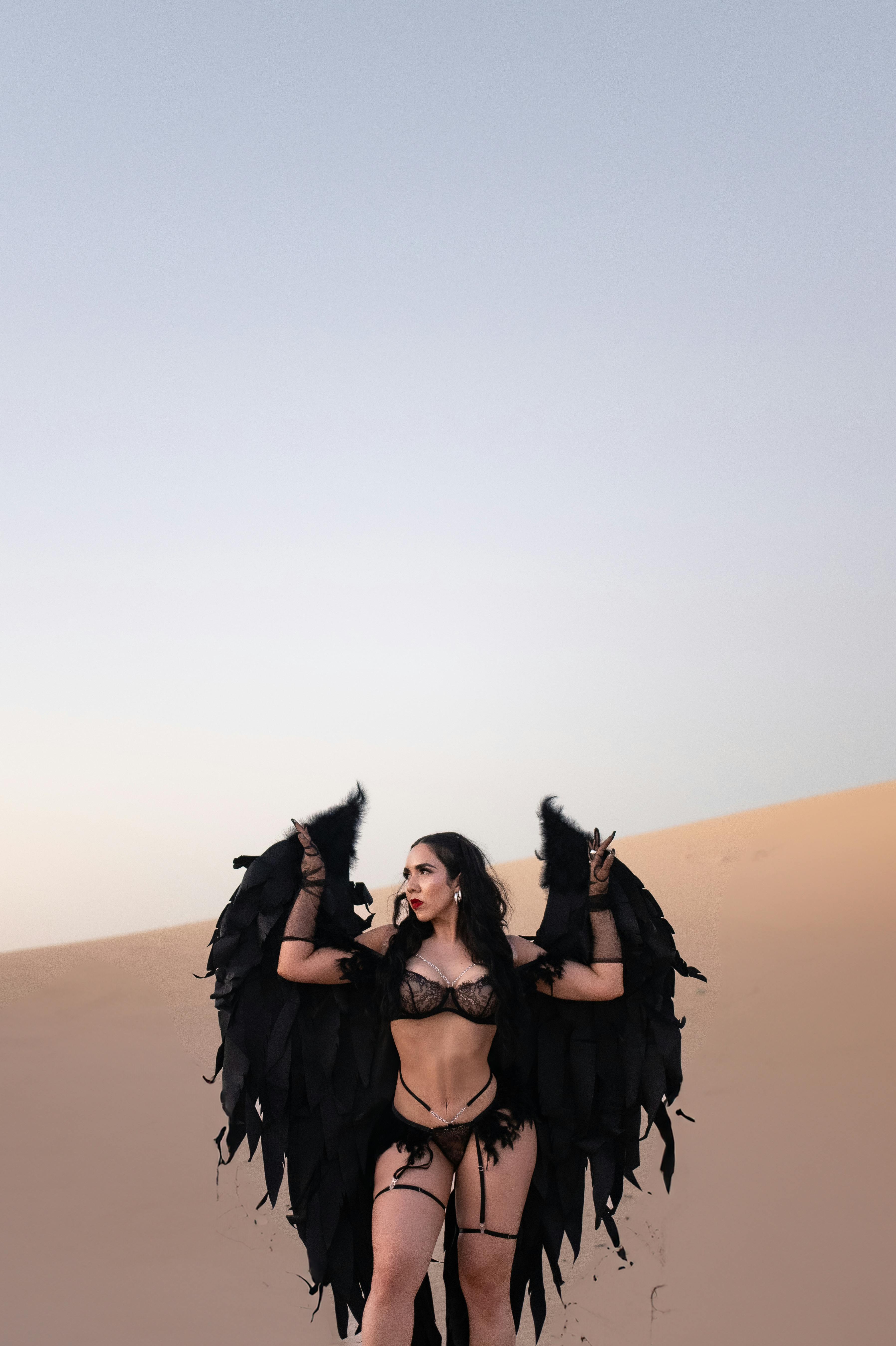 woman in black lingerie with black angel wings posing in a desert