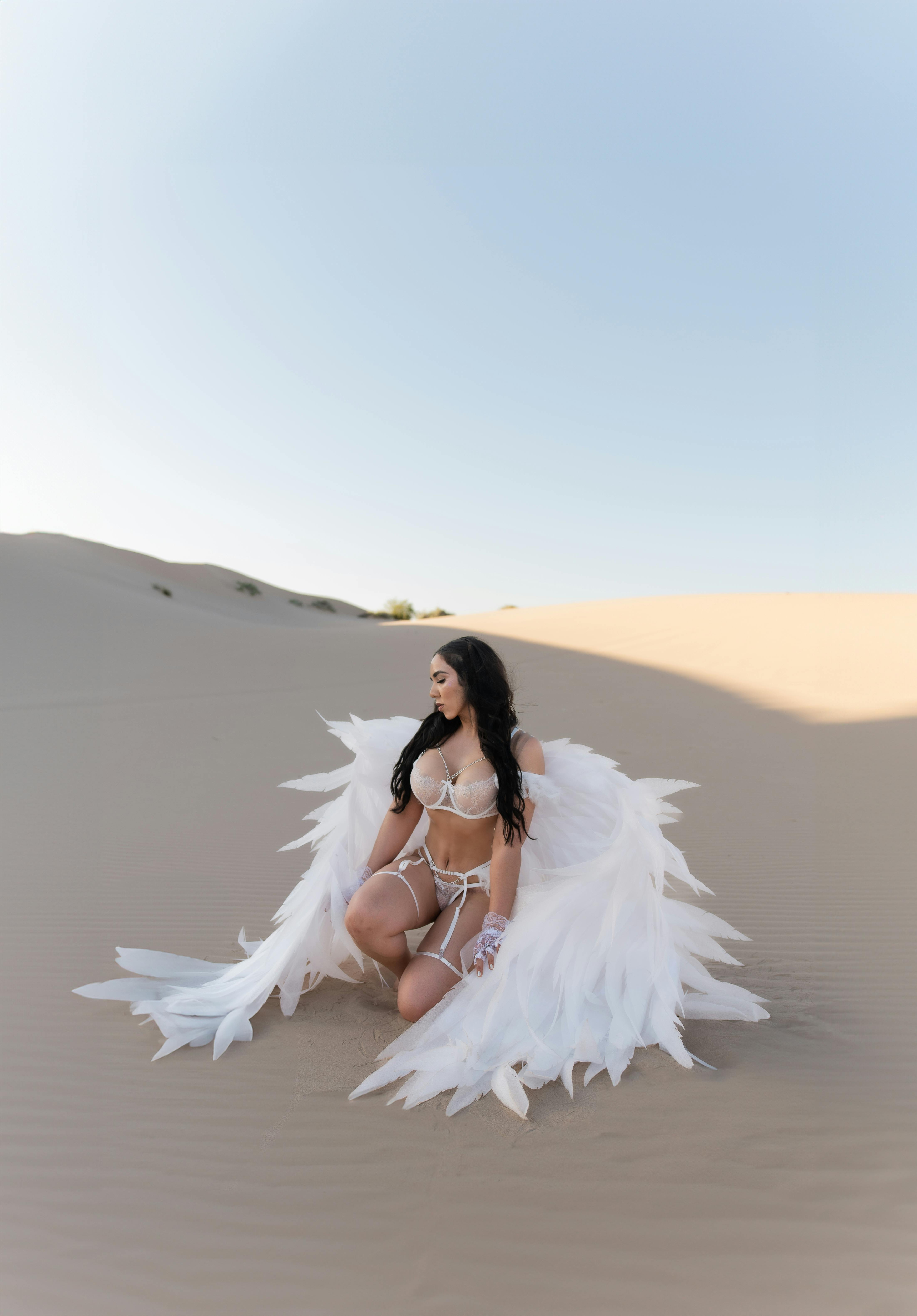 woman in white lingerie with white angel wings posing in a desert