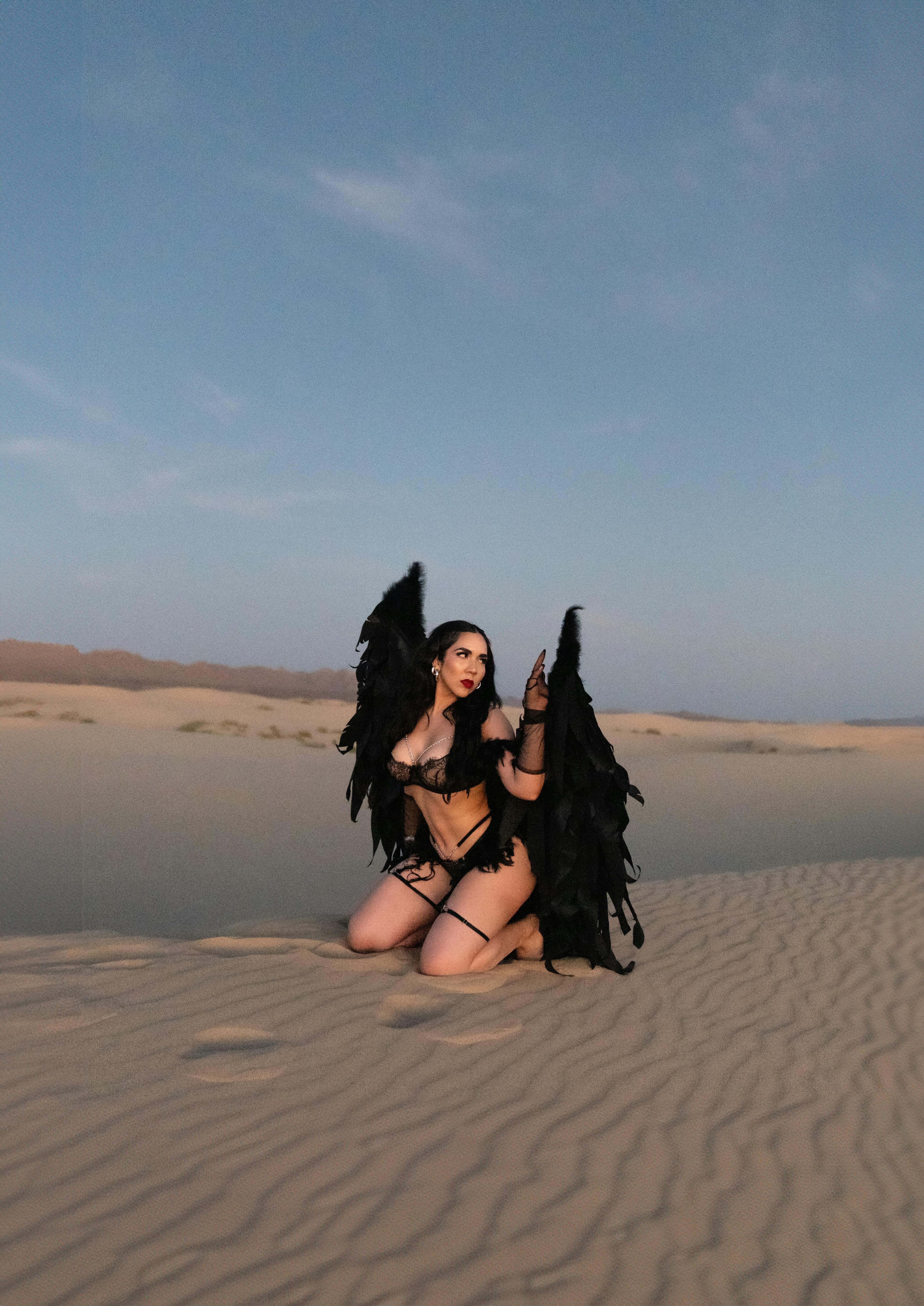 woman in black lingerie with black angel wings posing in a desert