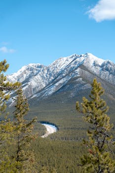 Breathtaking aerial view of snow-capped mountains and evergreen forest in Kananaskis, Alberta, Canada.