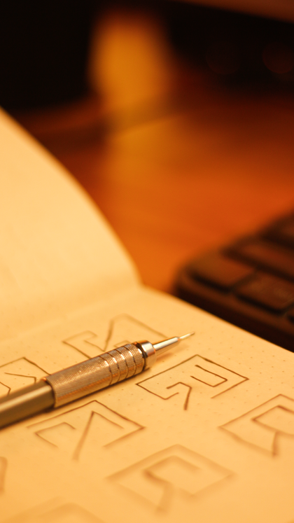 Pen resting on an open sketchbook of geometric drawings — photo by sandrin on Pexels