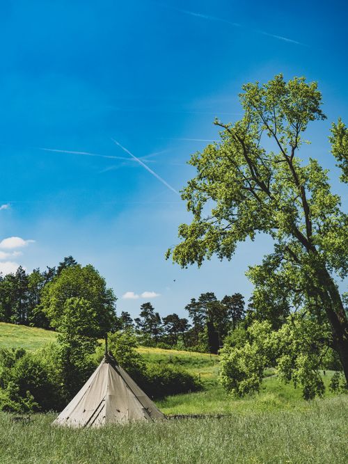 Free A tranquil tent setup in a lush green meadow under a bright blue sky in Teufen, Switzerland. Stock Photo