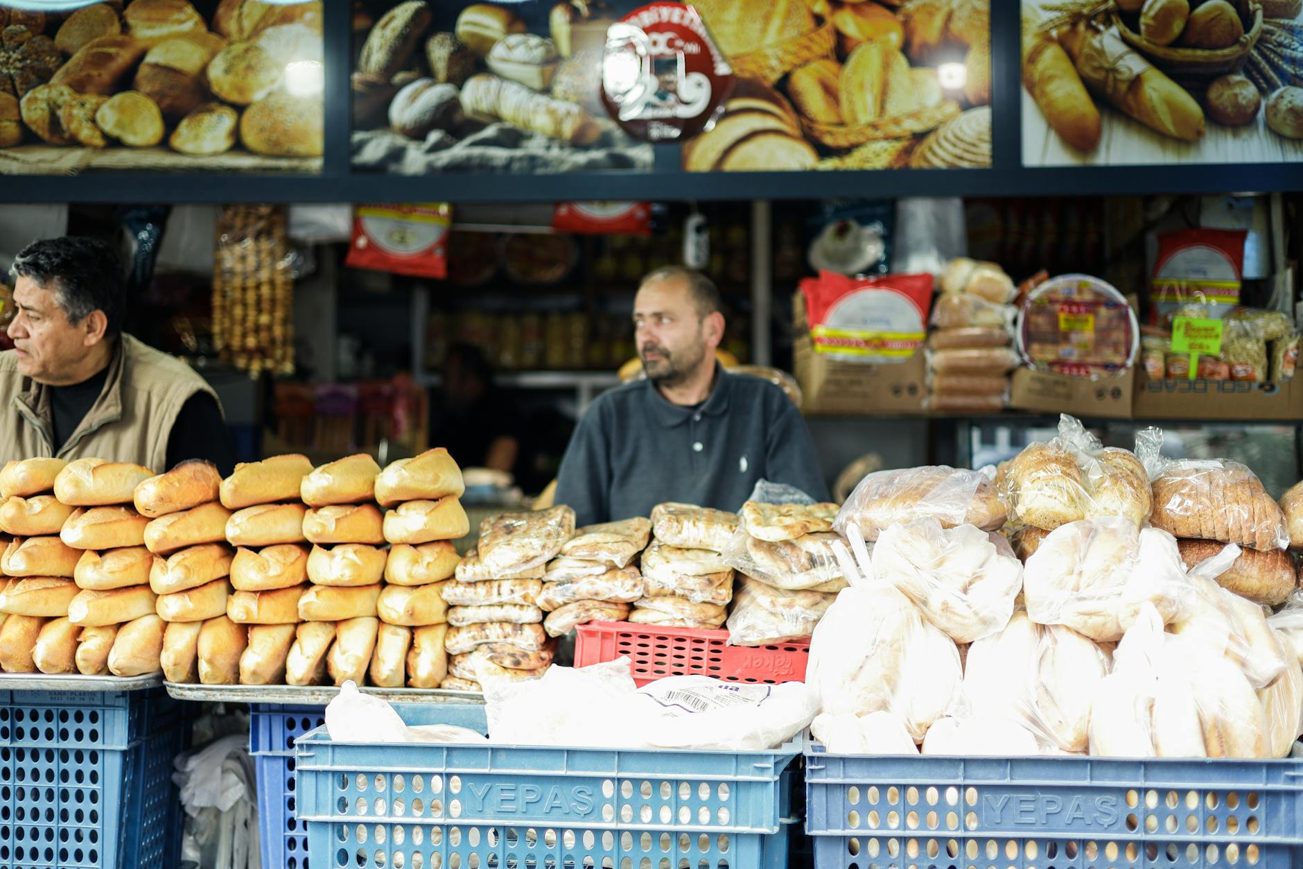 Vibrant market scene with two men selling assorted breads at an outdoor stall.