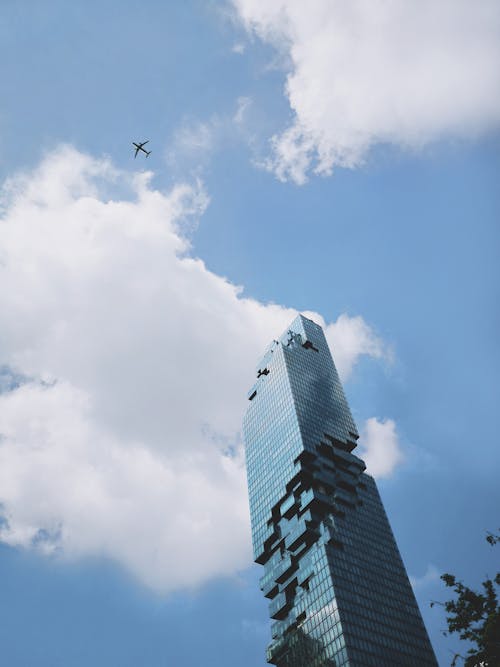 Free From below of aircraft flying in blue sky over modern city with futuristic skyscraper on sunny day Stock Photo