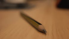 模糊特写视图中，铅笔躺在纹理木材表面