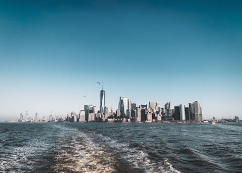 Stunning view of New York City skyline from the bay, with clear skies and urban skyscrapers.