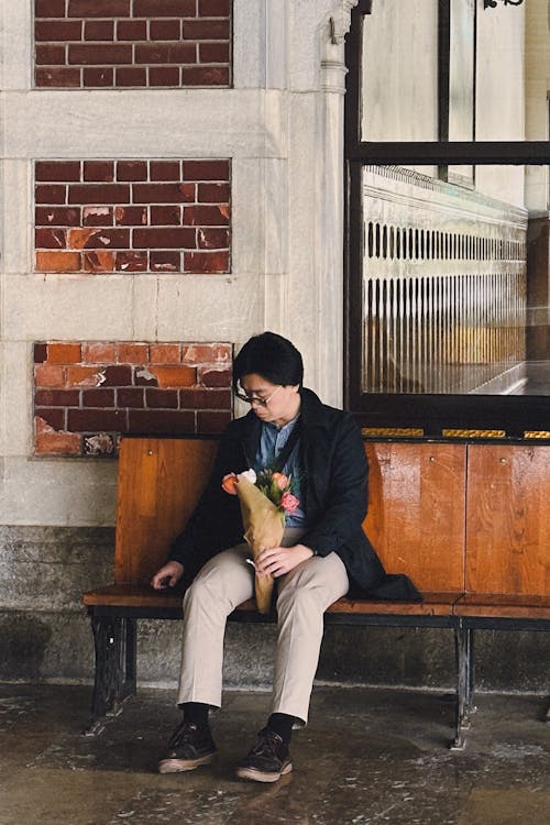 Free Candid Photo of a Man with a Bouquet Sitting on a Bench  Stock Photo