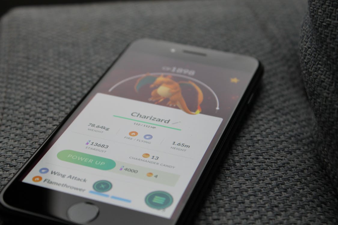 Kostenlos Eingeschaltetes I Phone Mit Pokemon Go Charizard Anwendung Stock-Foto