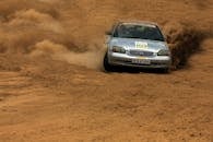 在激动人心的越野比赛场景中，一辆汽车在沙漠地形中加速，扬起阵阵灰尘