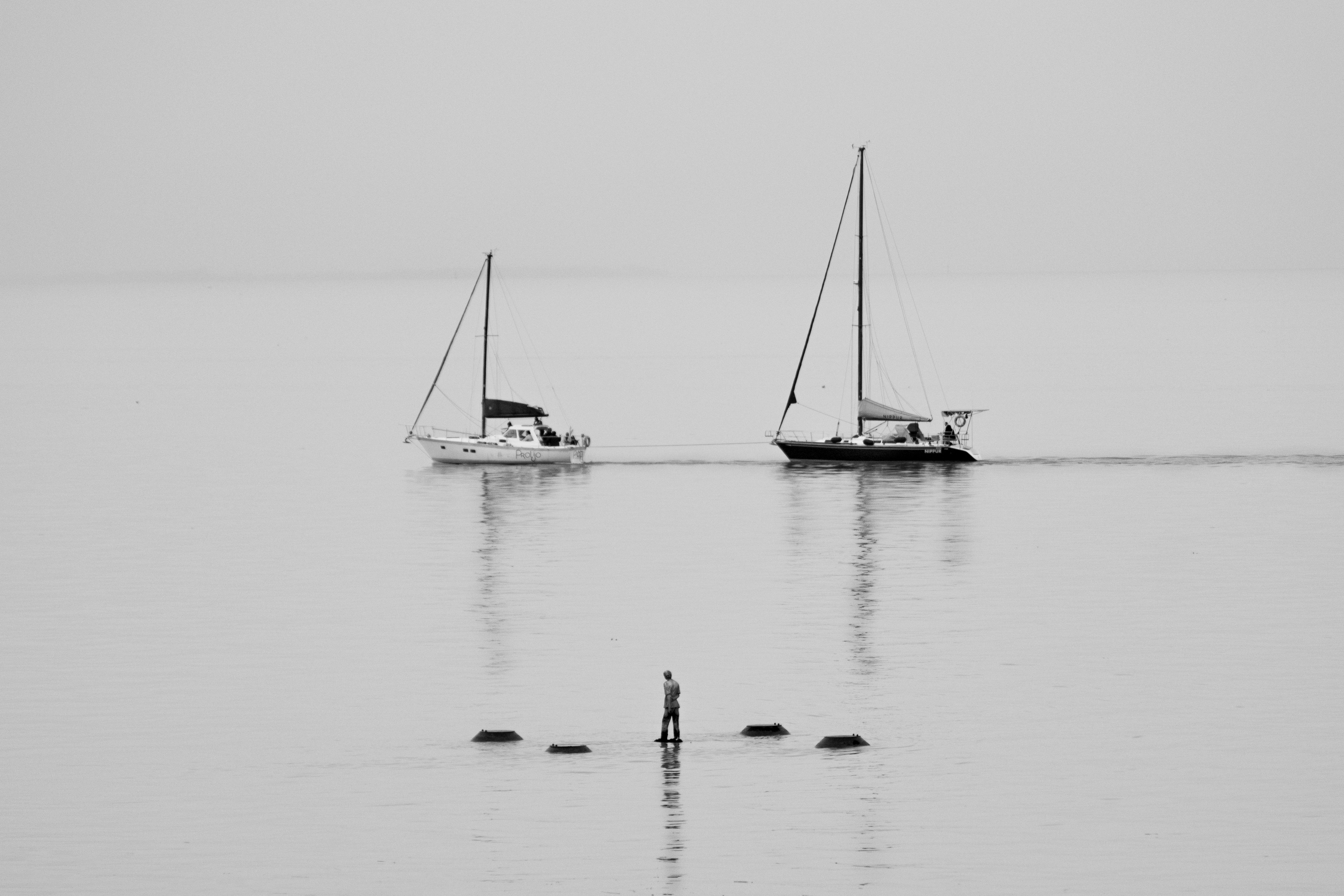 Artistic black and white image of sailboats on the Buenos Aires coastline with a solitary figure.