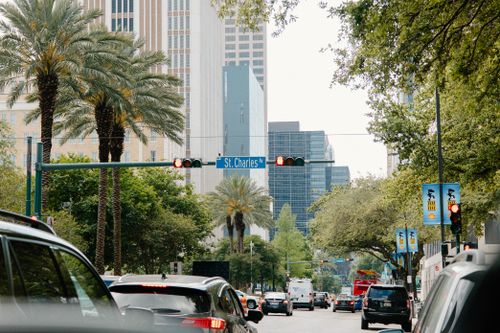 Free Traffic on St. Charles Avenue, New Orleans showcasing palm trees and modern architecture. Stock Photo