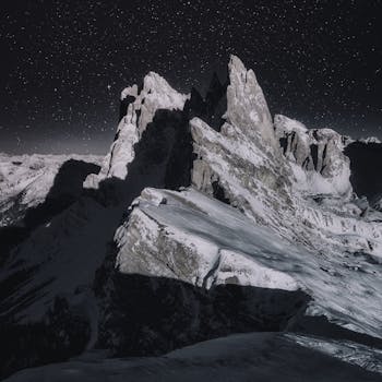 Dramatic night view of snow-capped peaks in the Italian Alps under a starry sky.