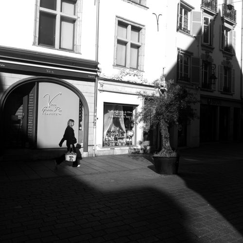 Free A woman walks through a sunlit street in Nancy, capturing urban life. Stock Photo