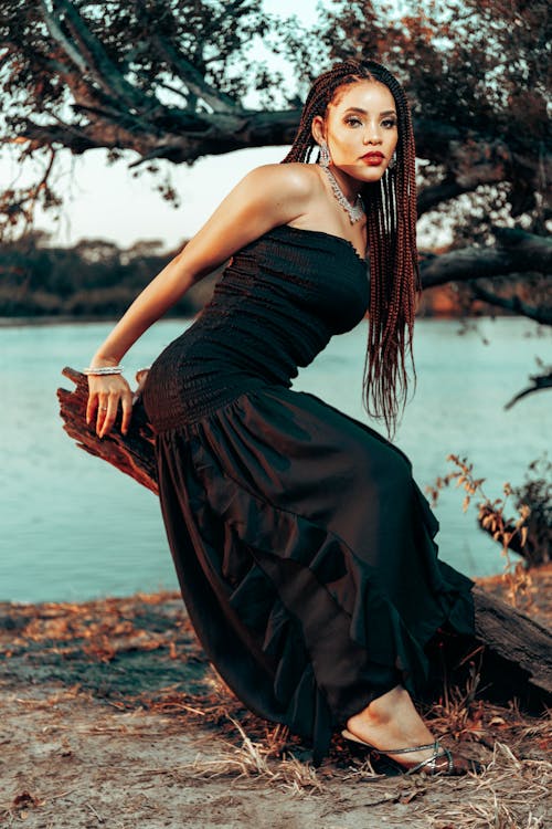 A woman in a black dress sitting on a log