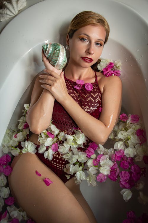 A woman in a bathtub with flowers and a rose