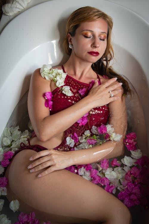 A woman in a red dress laying in a bathtub with flowers