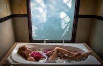 A woman laying in a bathtub with a flower in her hair