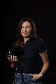 Portrait of a woman photographer holding a camera in a dark studio background.