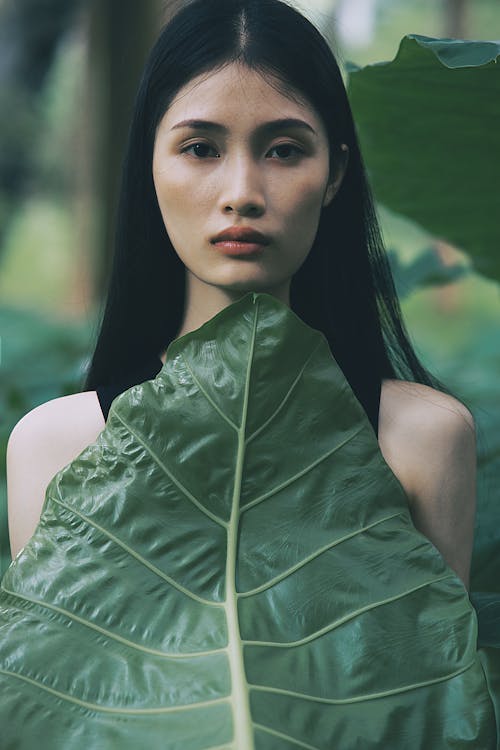 A woman with long black hair and green leaves
