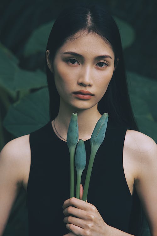 A woman in black holding two blue flowers