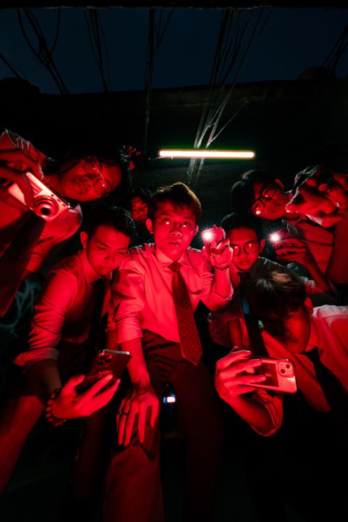 Free Group of young adults investigating a scene with smartphones and cameras under red lighting. Stock Photo