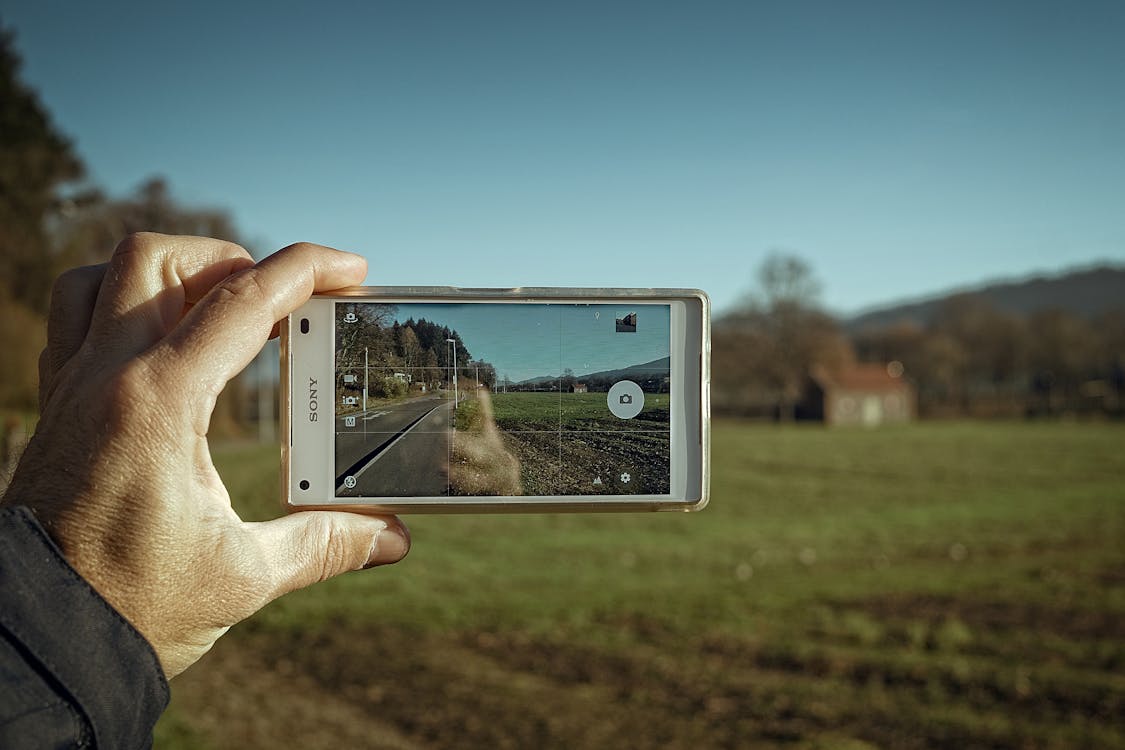 Gratis Orang Yang Memegang Smartphone Sony Putih Foto Stok