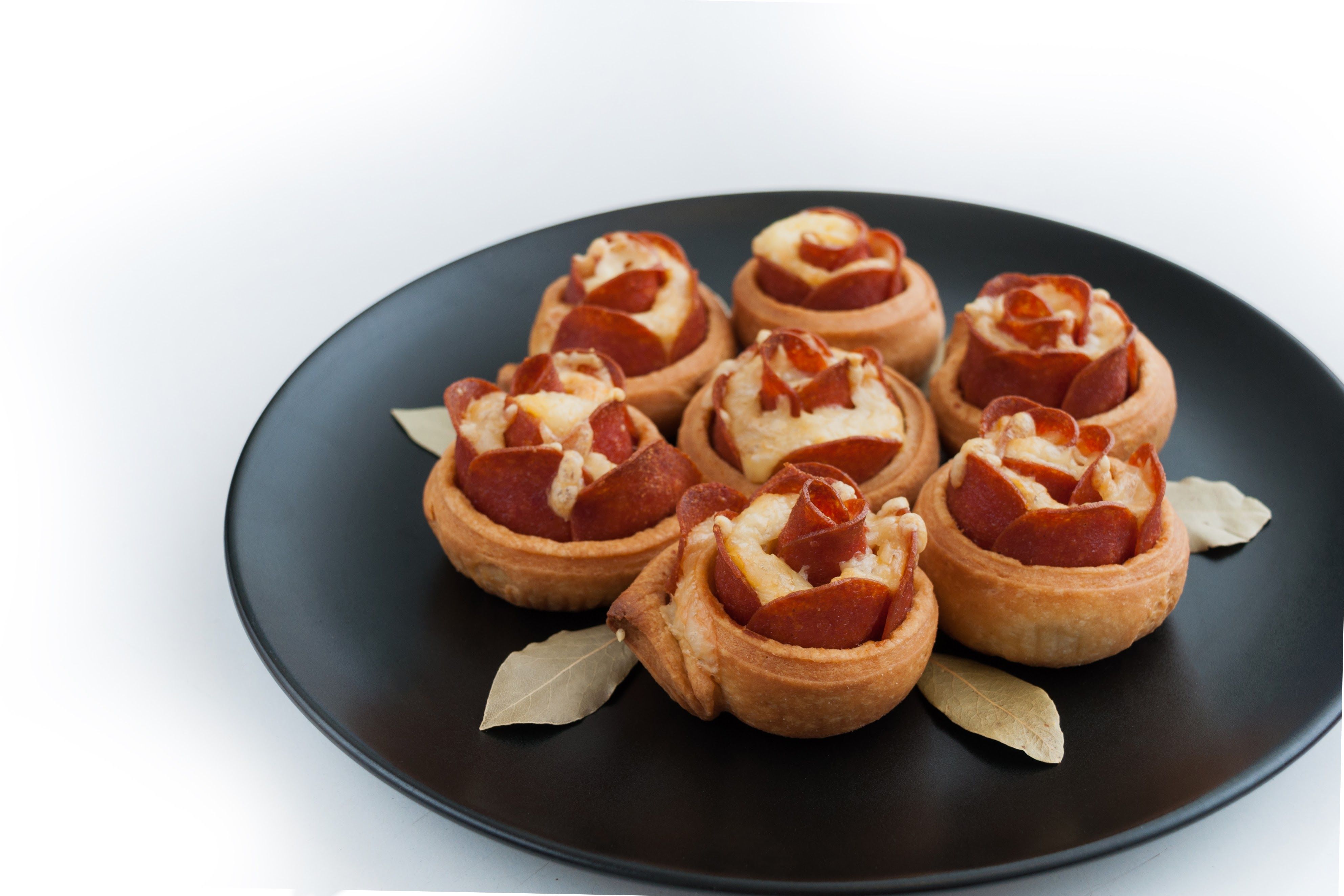 Delicious baked pepperoni and cheese pastries on a black plate, perfect for elegant appetizers.