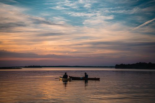 Free Two kayakers enjoy a serene sunset on Saint-Armel Lake in Bretagne, France. Stock Photo