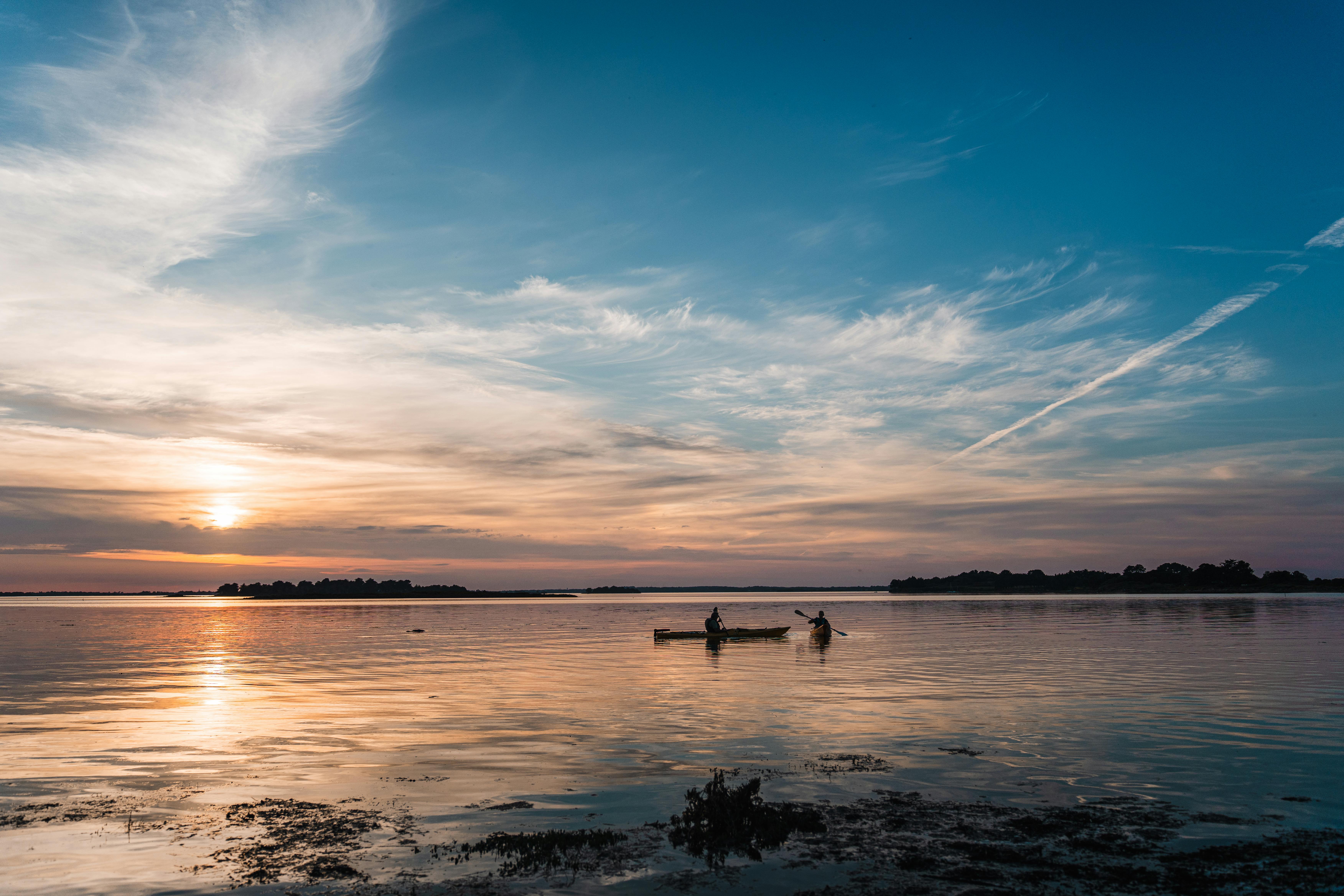 Serene sunrise kayaking on a calm lake in Saint-Armel, Bretagne, France.