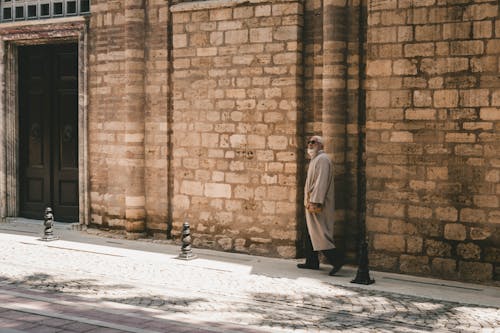 A man in a coat walking down a street