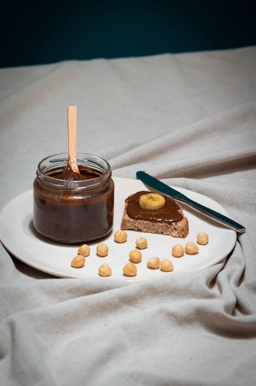 A jar of peanut butter and a spoon on a plate