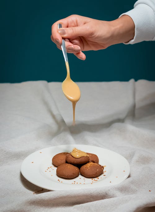 A person pouring a sauce on a plate with cookies