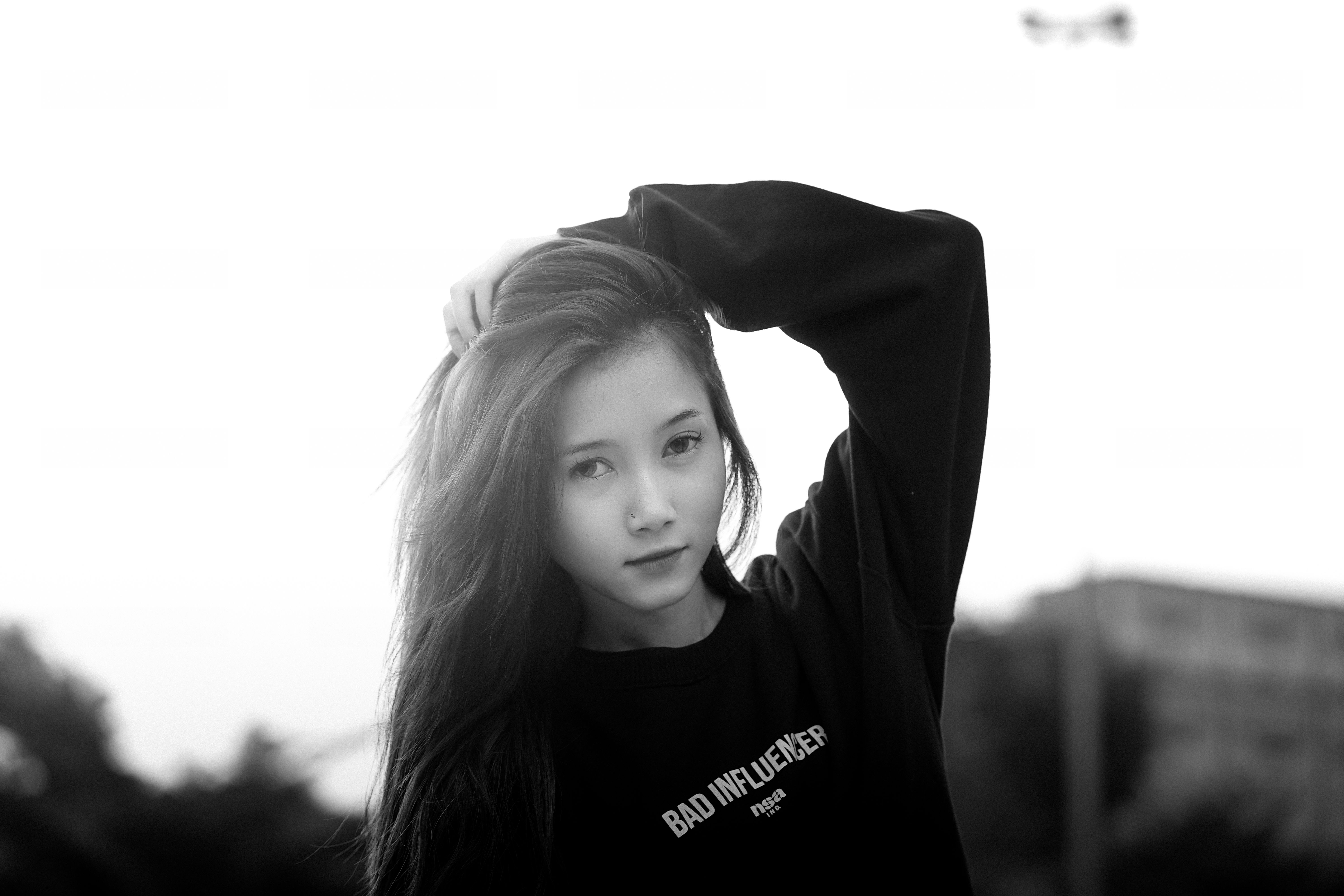 Elegant black and white portrait of a young woman outdoors, exuding fashion and confidence.