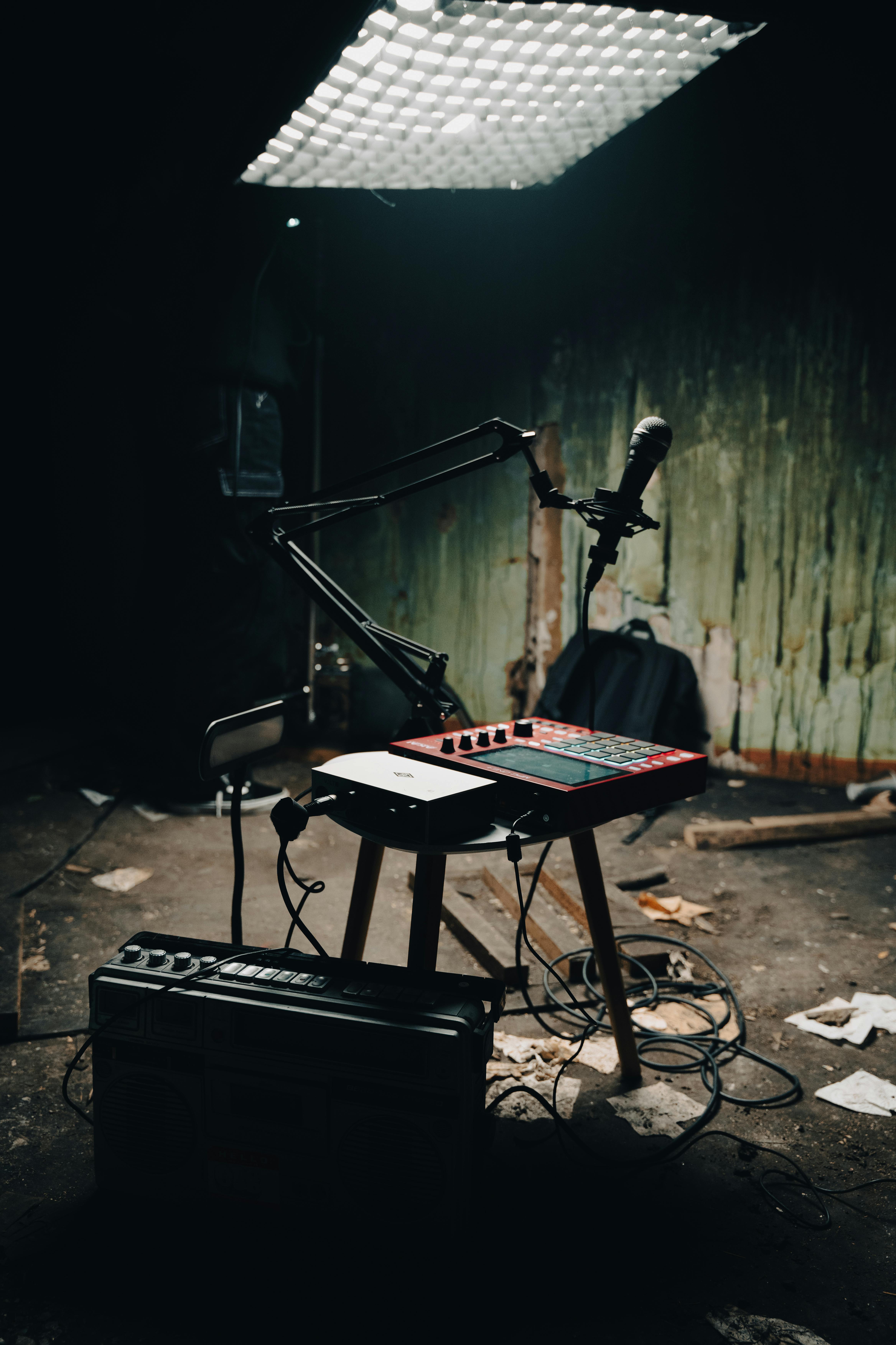 A deserted room with music production equipment setup on a stool, featuring a microphone and pad controller.